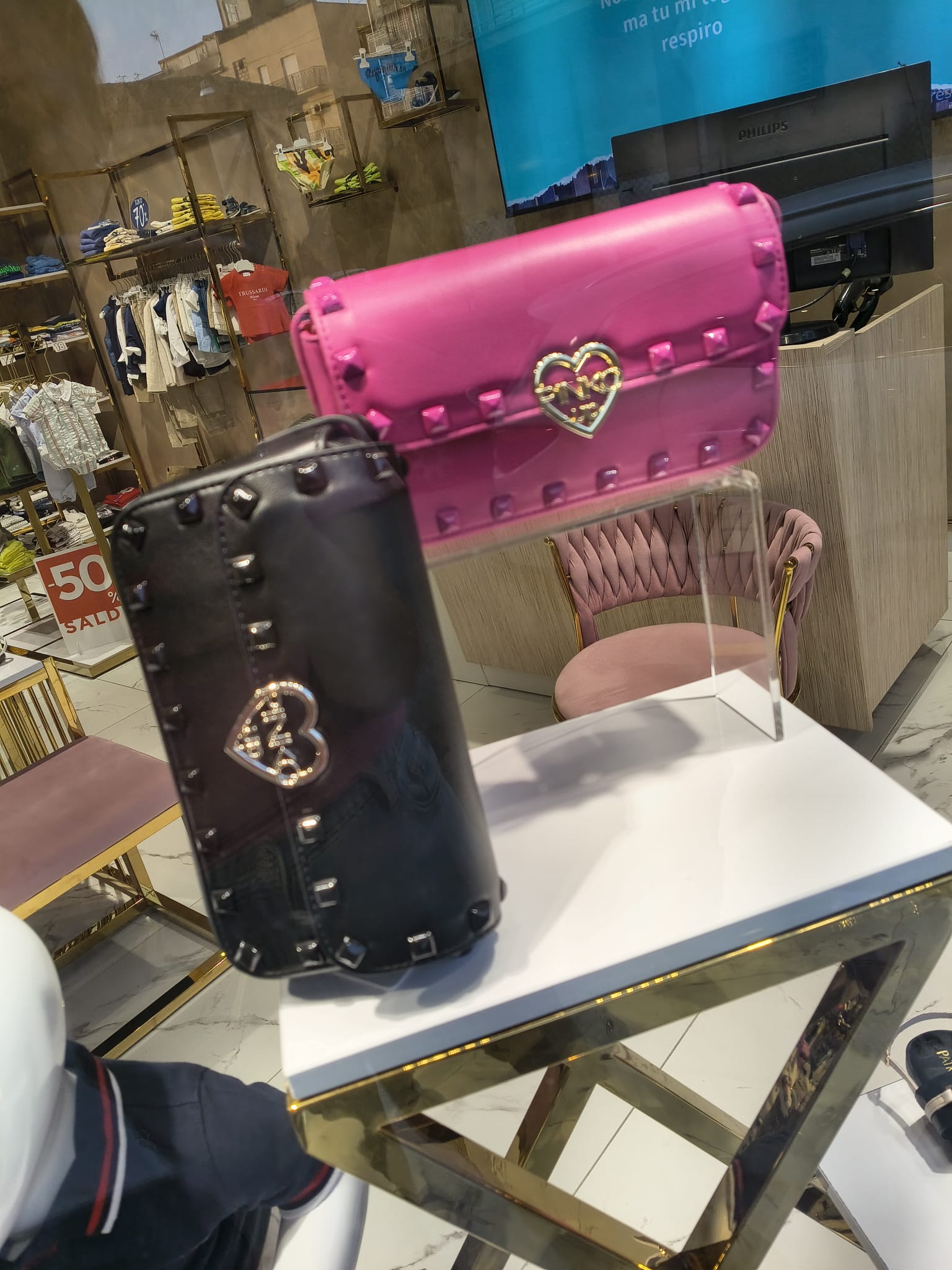 Borsa Pinko fucsia con borchie e borsa Blauer nera esposte in vetrina, in saldo